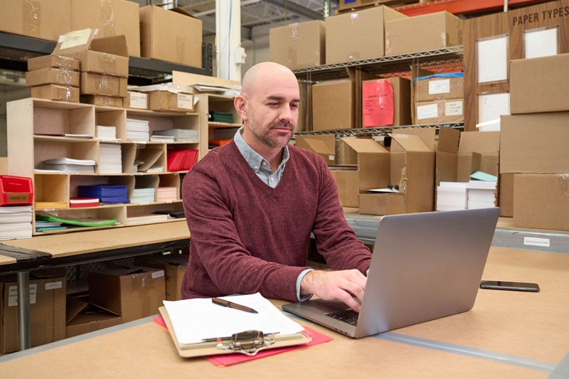 Man working in stock room on his laptop